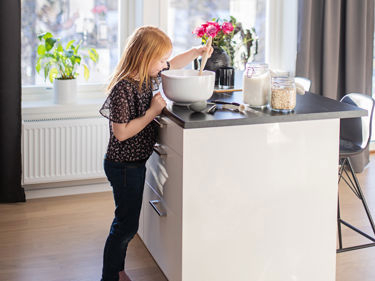 Bilde av jente som baker kake ved kjøkkenøy på kjøkkenet