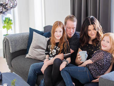 Bilde av en familie som sitter samlet i sofaen sin
