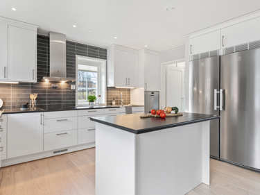 Bilde av kjøkken med kjøkkenøy, opphøyd oppvaskmaskin og kjøl / frys i rustfritt stål