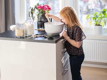 Bilde av barn som baker kake ved kjøkkenøy på kjøkkenet