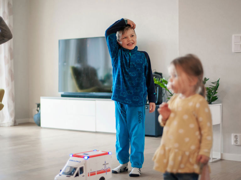 Bilde av barna til familien som står i stua i et helt nytt hus