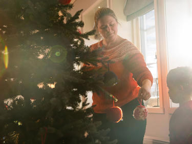 Bilde av mor som hjelper sønnen å pynte juletreet