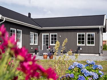 Bilde av et Älvsbyhus og hagen utenfor med masse blomster