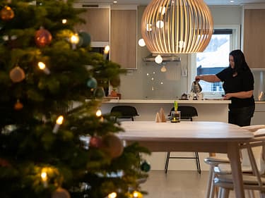 Bilde av juletre med mor som ordner kaffe i bakgrunnen