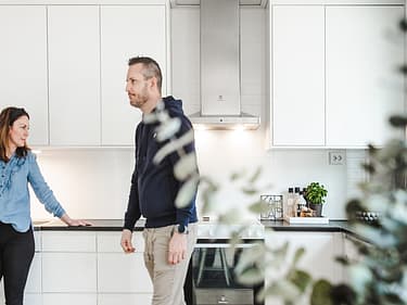 Bilde av huseiere på kjøkkenet med en plante foran i bildet