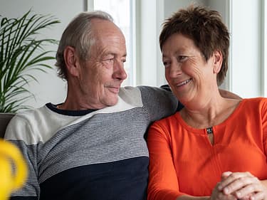 Bilde fra kundecase med paret som sitter smilende i sofaen