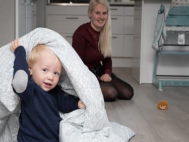 bilde av eldste sønnen som leker med en dyne på gulvet