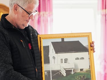 Bilde av huseier som viser frem et bilde av det gamle barndomshjemmet sitt