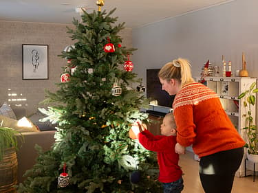Bilde av mor som hjelper sønnen å pynte juletreet