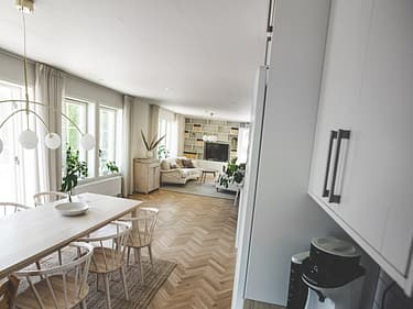 Bilde som viser litt av kjøkkenet, spisegruppen og stuen