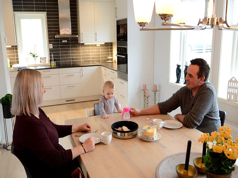 Bilde av en familie som sitter rundt kjøkkenbordet å spiser
