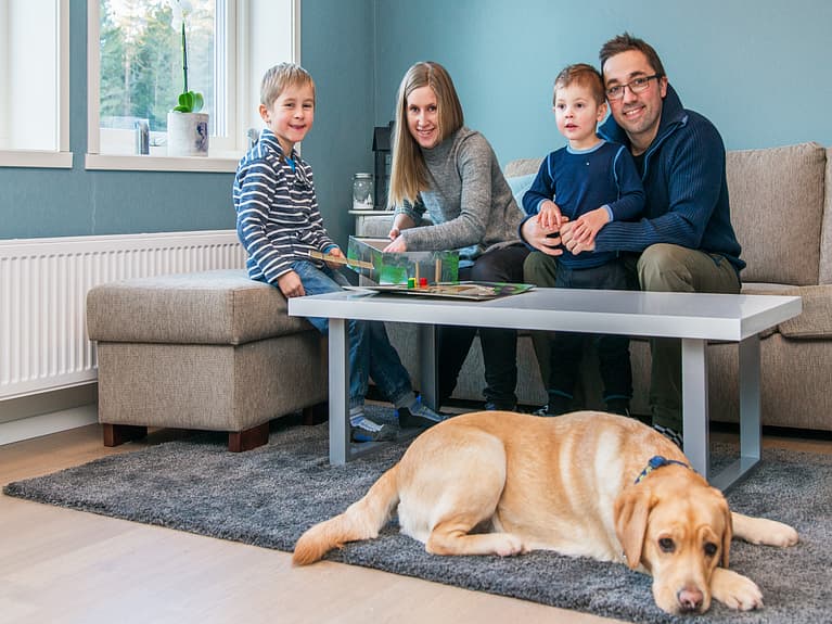 Bilde av familien samlet i sofaen mens hunden sover på gulvteppet